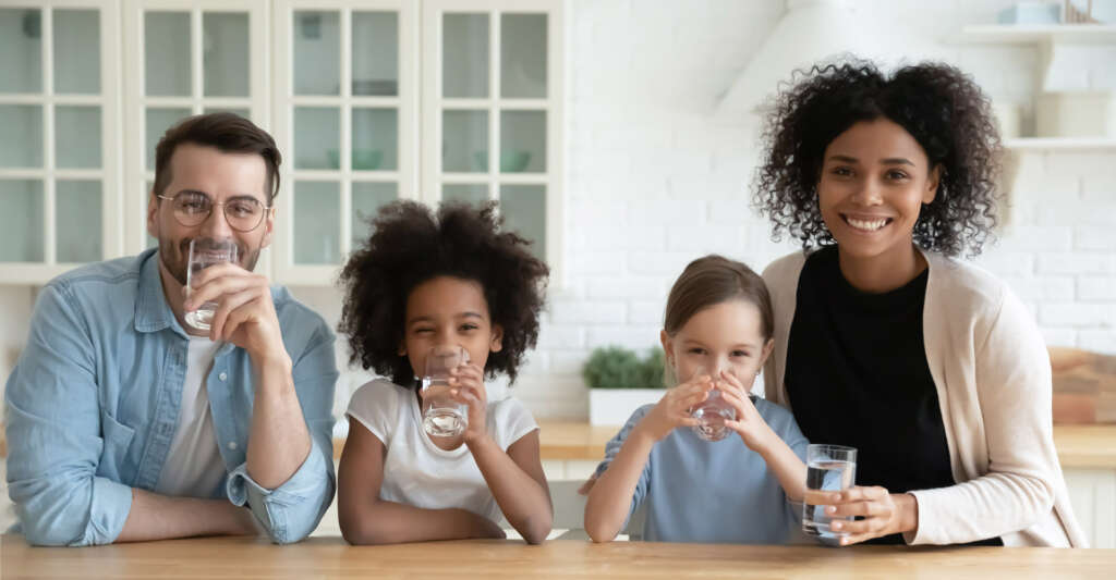 Parents and two daughters drinking a glass of clean filtered water