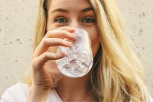 A woman drinking a glass of clean water filtered with her whole house water system