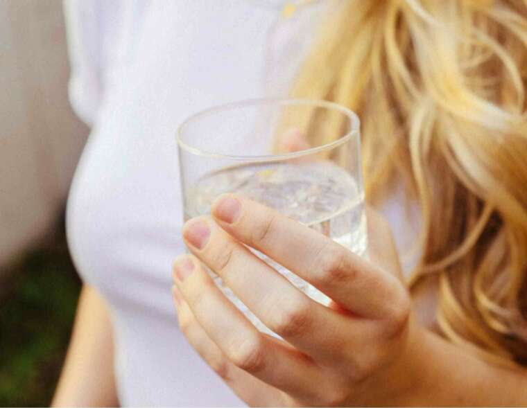 A woman holding a glass of water