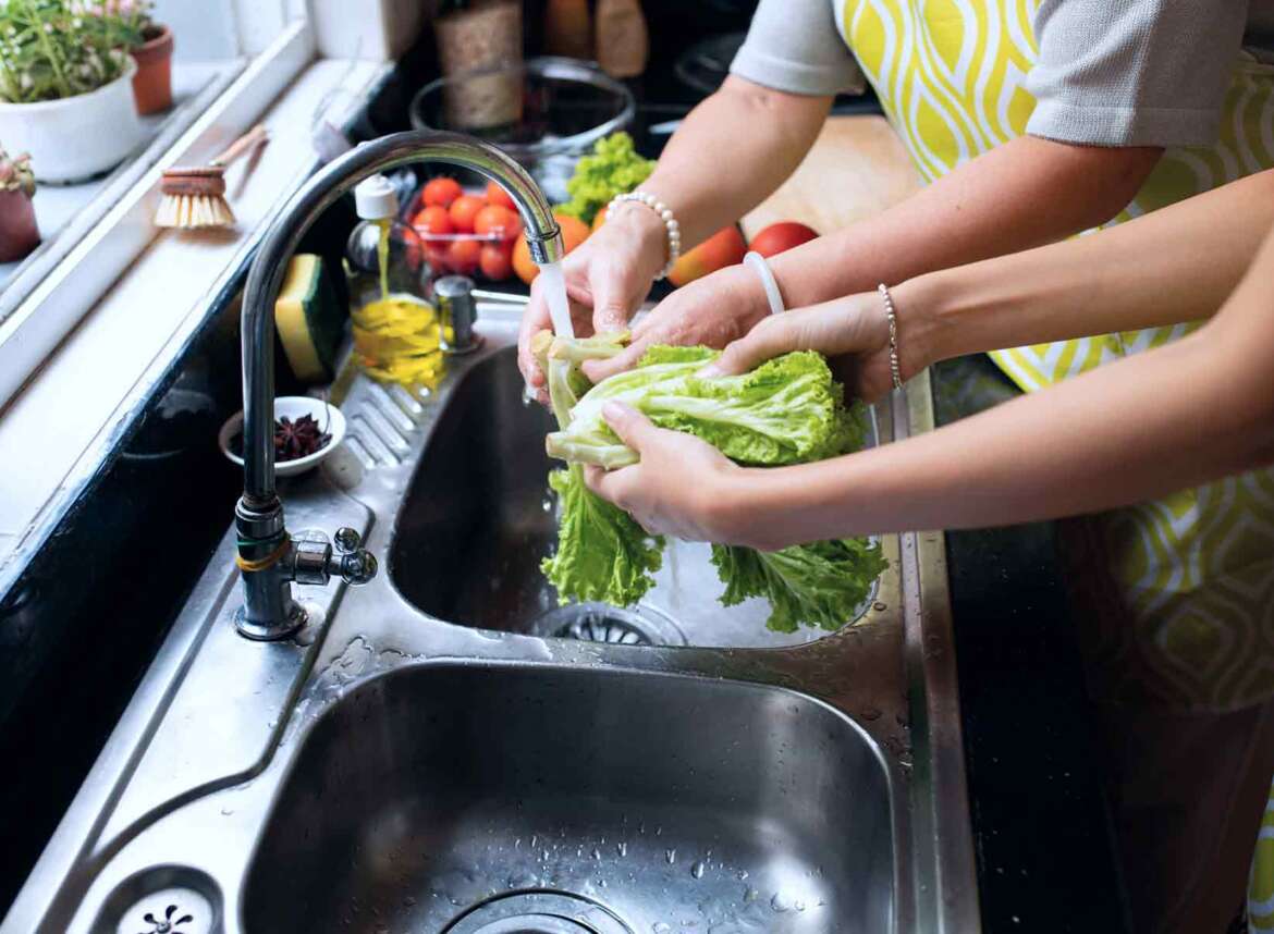 Two person bonding moment in the kitchen, washing vegetables together at the faucet