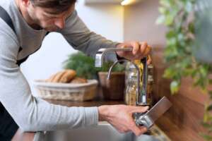 A man checking his kitchen faucet