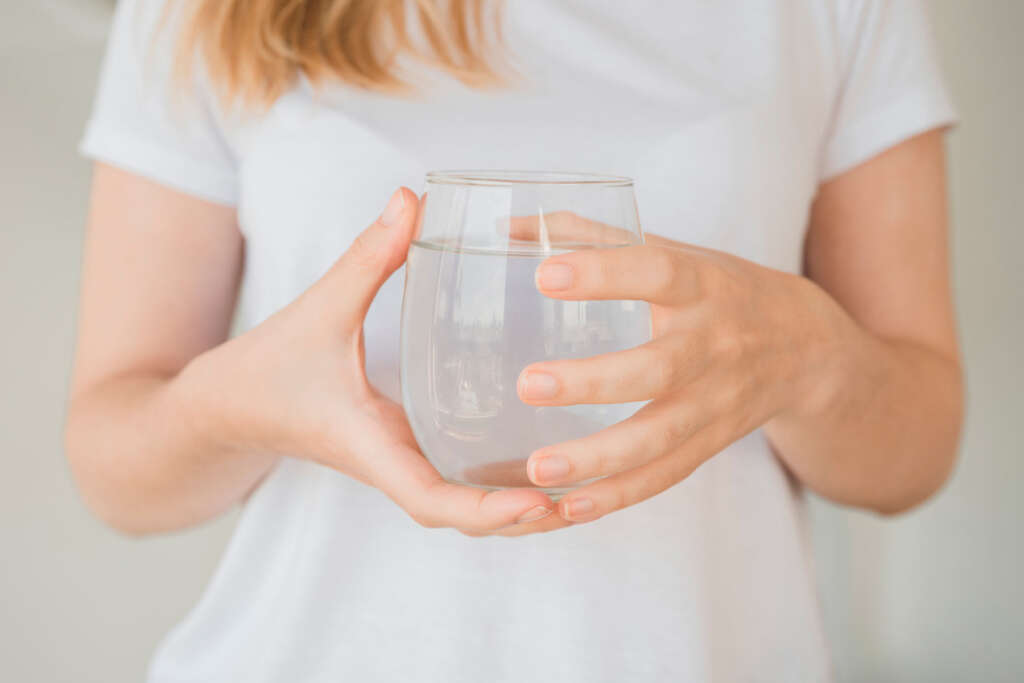 A woman holding a glass of clean, chlorine-filtered water