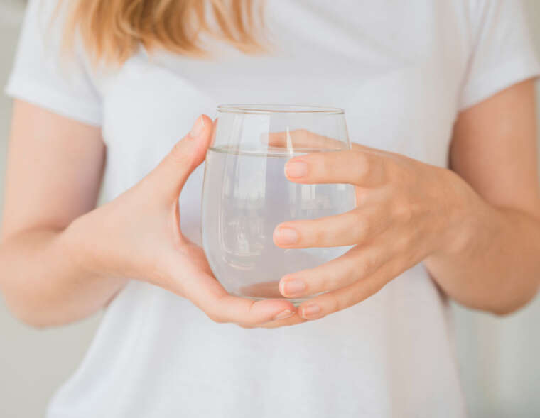 A woman holding a glass of clean, chlorine-filtered water