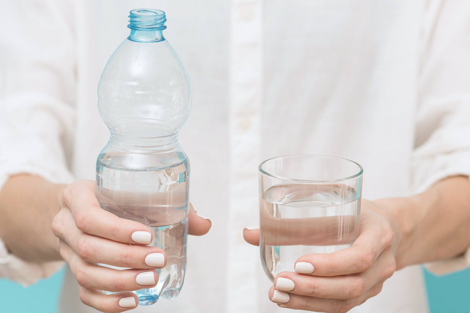 A person holding a glass of water and a bottle of water