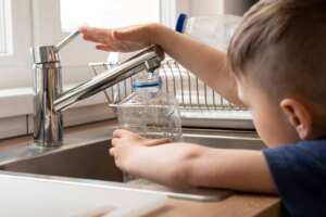 A boy filling water from a tap