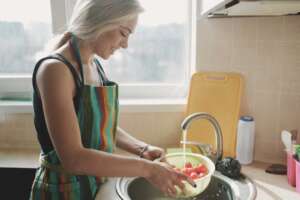 A woman is washing tomatoes in running softened water