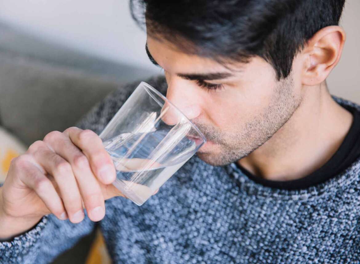 A man is drinking a glass of softened water