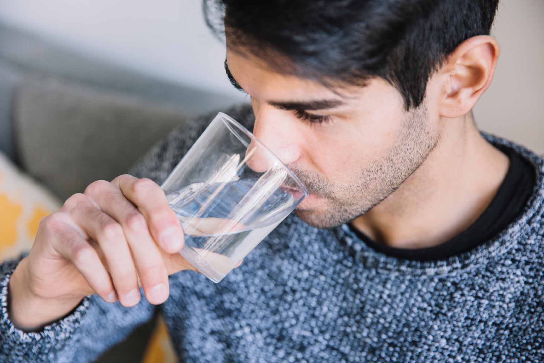 A man is drinking a glass of softened water