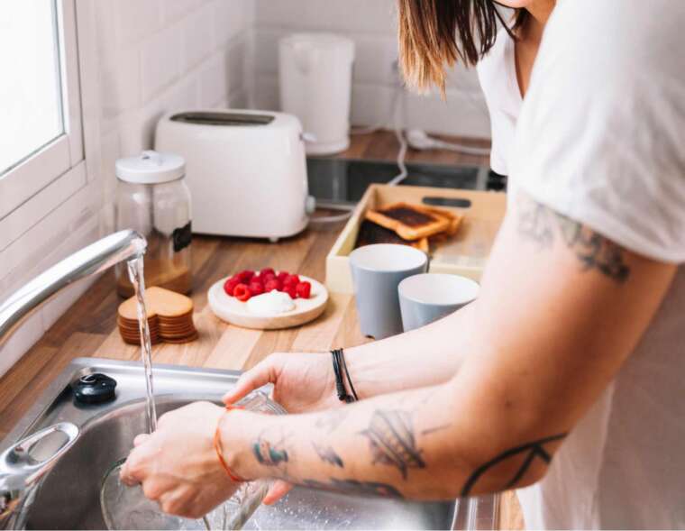 A woman washing in the kitchen sink using water filtered by a UV water filter