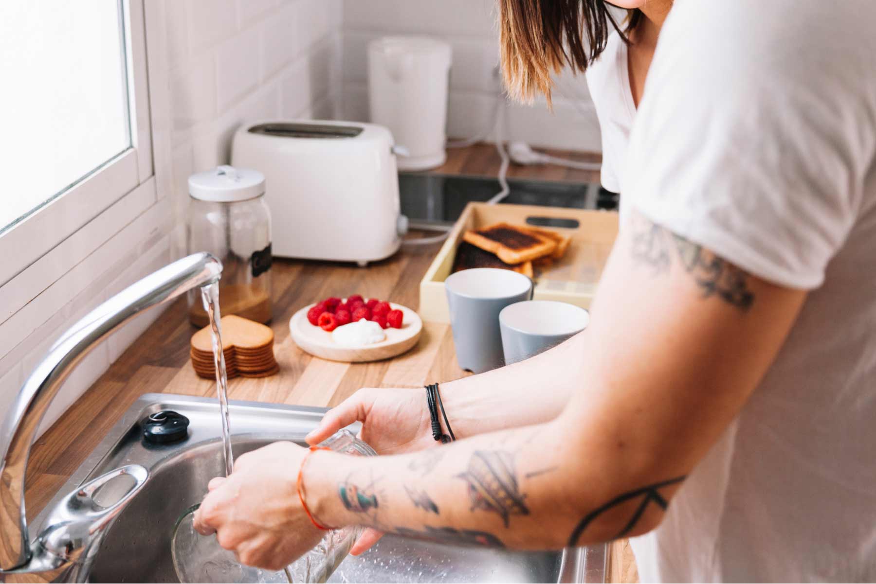 A woman washing in the kitchen sink using water filtered by a UV water filter