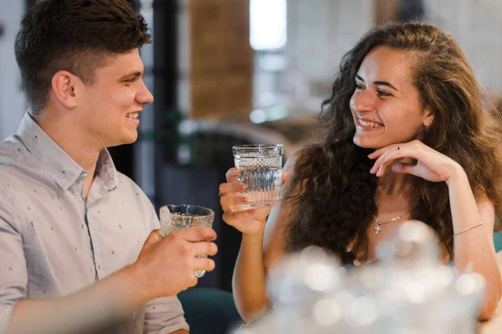 A man with a glass of water filtered using a salt-free water softener & a woman with a glass of water filtered using a salt-based water softener