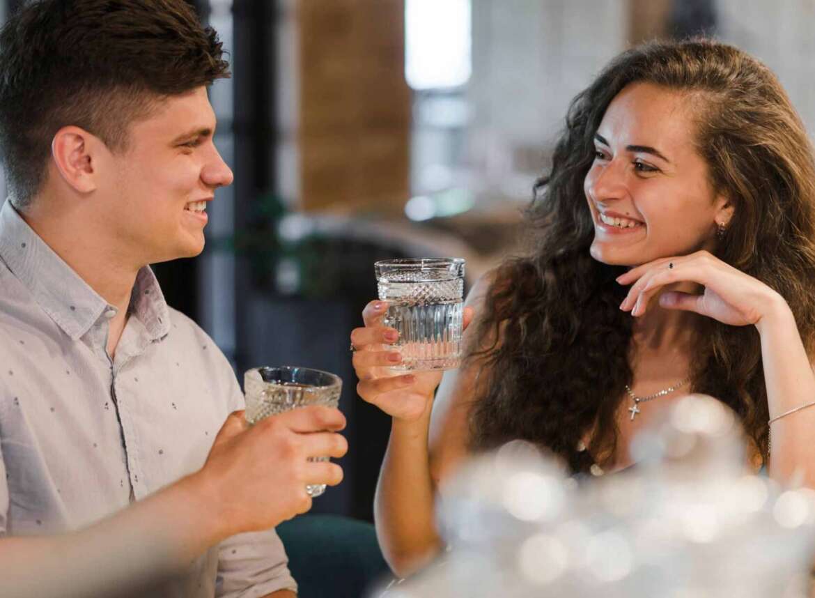 A man with a glass of water filtered using a salt-free water softener & a woman with a glass of water filtered using a salt-based water softener