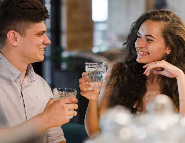 A man with a glass of water filtered using a salt-free water softener & a woman with a glass of water filtered using a salt-based water softener