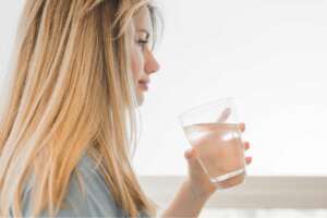 A woman holding a glass of water filtered through a UV water filtration system