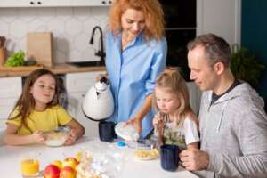 A family with two daughters is eating breakfast with clean, filtered water