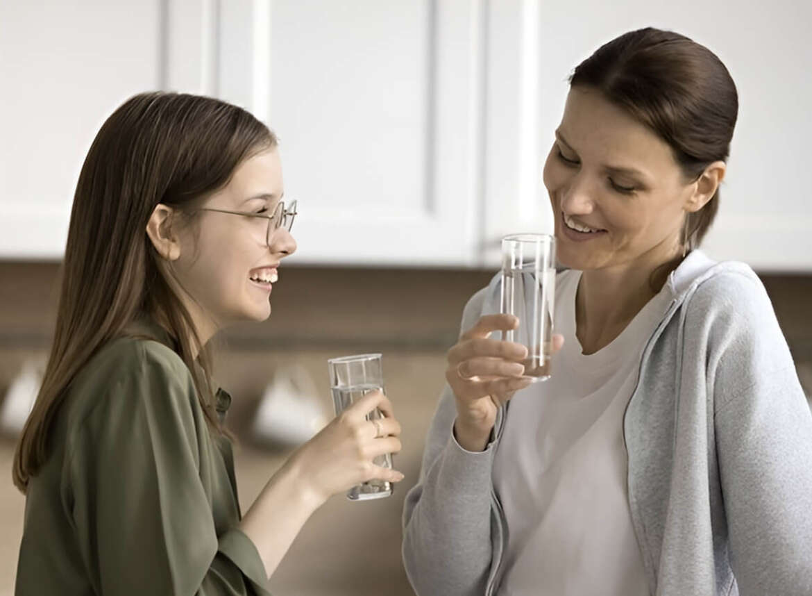 Two women engage in conversation, savoring their filtered water