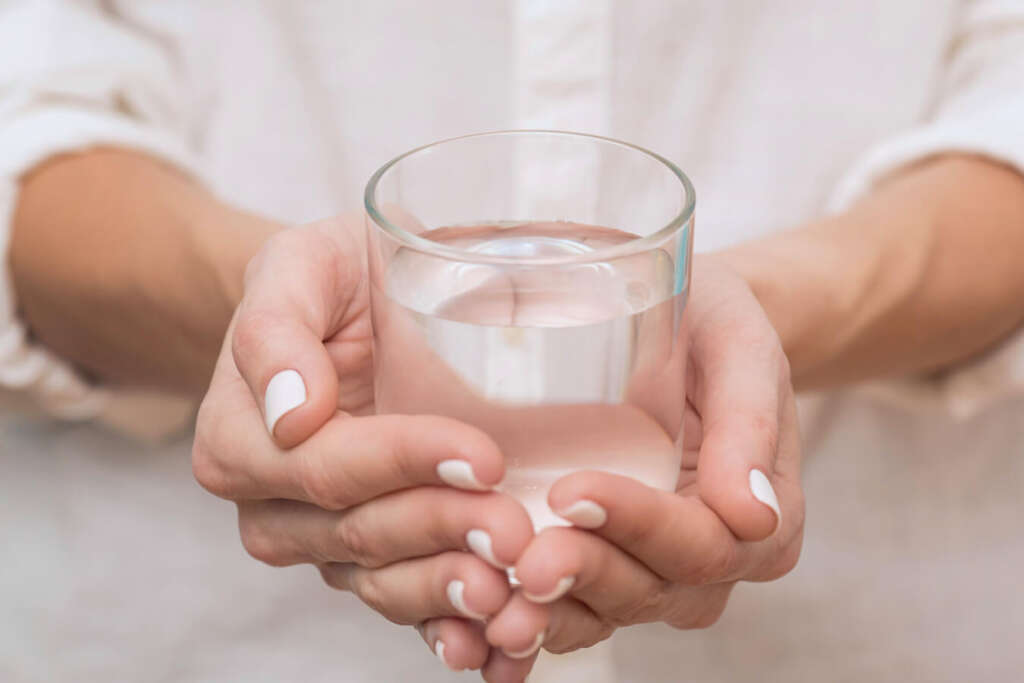 A woman holding a glass of treated acidic water