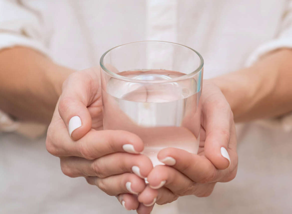 A woman holding a glass of treated acidic water