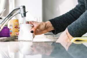 A lady getting a glass of water from the kitchen faucet