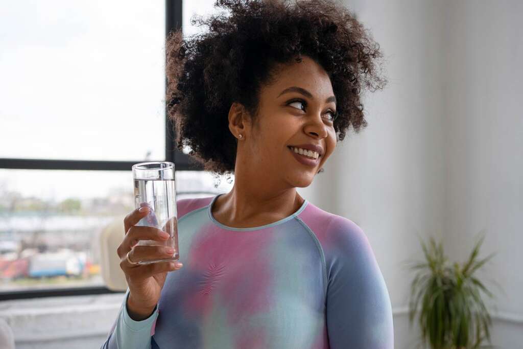Smiling woman holding a glass of chlorine-free water filtered with carbon filter