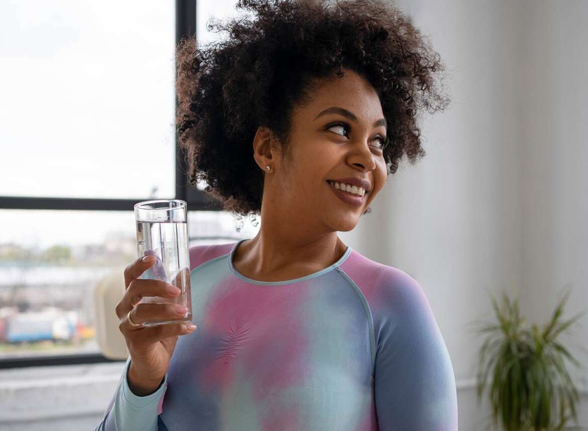 Smiling woman holding a glass of chlorine-free water filtered with carbon filter