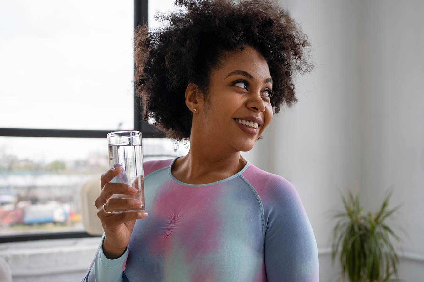 Smiling woman holding a glass of chlorine-free water filtered with carbon filter