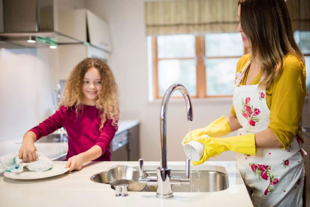 A mother and child washing dishes in the kitchen with filtered tap water