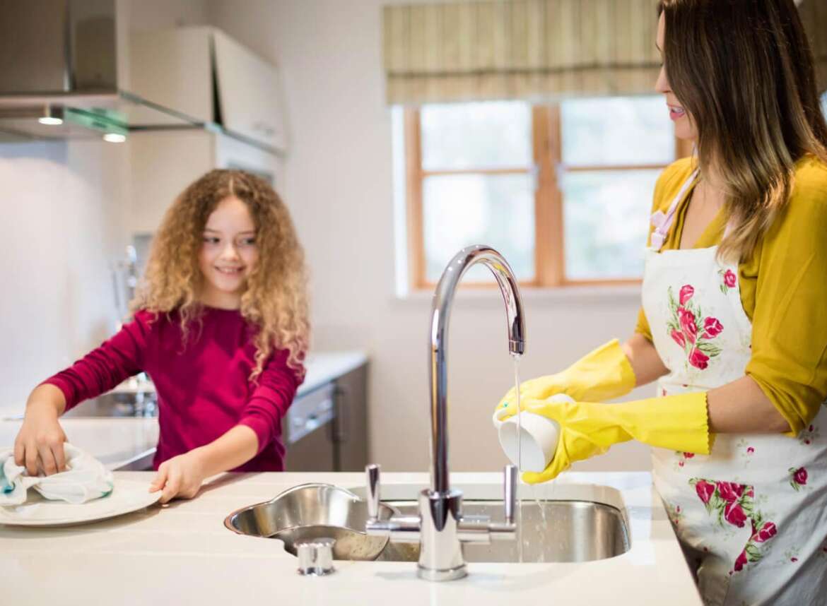 A mother and child washing dishes in the kitchen with filtered tap water