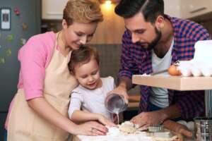 Father, mother, and daughter making baked goods together