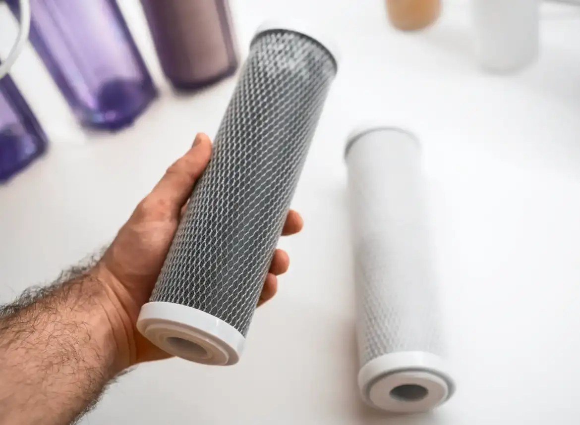 A man's hand holding a carbon cartridge replacement filter