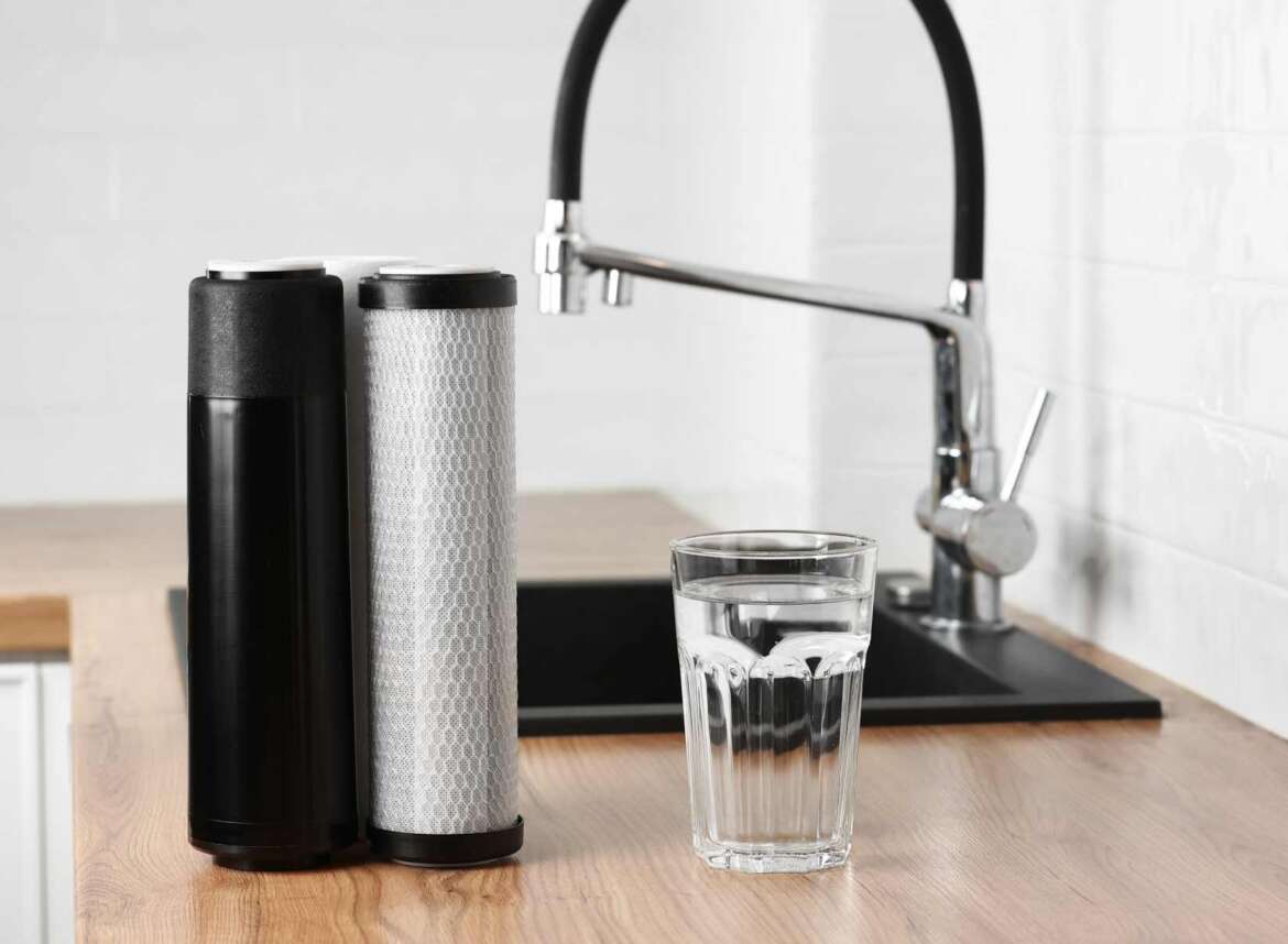 Reverse osmosis (RO) filter cartridges beside a glass of clean filtered drinking water